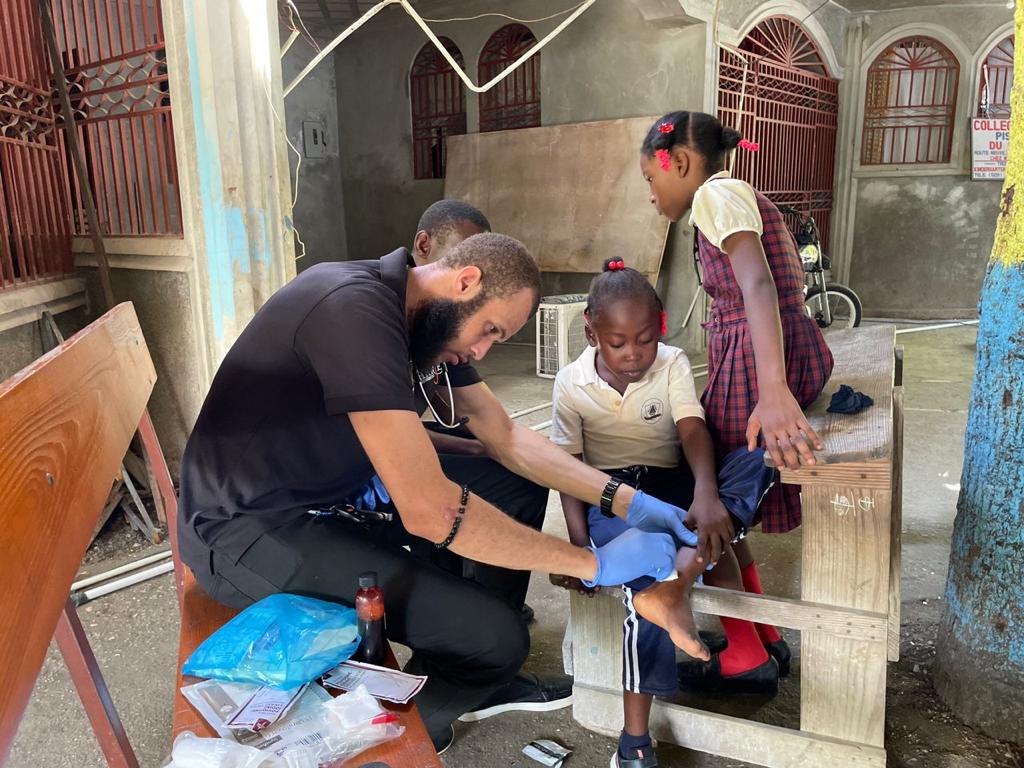 haitian doctor treating wound on childs leg